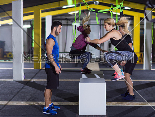 group of young healthy athletic people training jumping on fit box at crossfitness gym