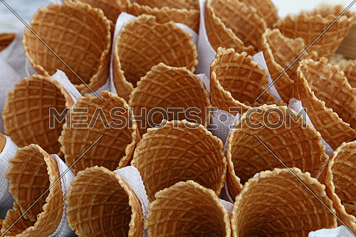 Several empty fresh wafer ice cream cone cornet cups with white paper napkins, close up, elevated high angle view