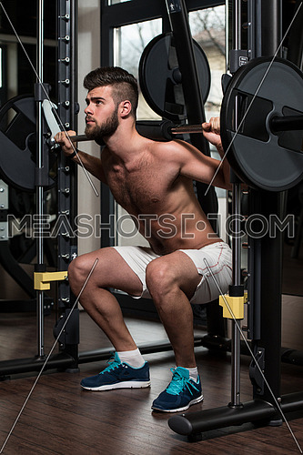 Young Man Performing Barbell Squats - One Of The Best Bodybuilding Exercise For Legs