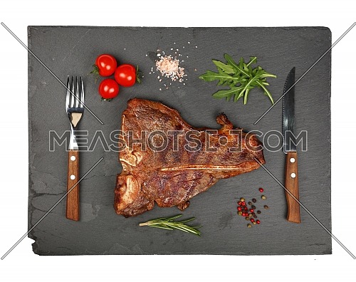 Close up one big grill roasted T-bone porterhouse beef steak with rib bone served on black slate cutting board isolated on white background, elevated top view, directly above