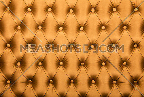 Golden orange capitone textile background, retro Chesterfield style checkered soft tufted fabric furniture diamond pattern decoration with buttons, close up