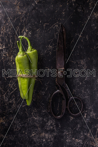 A green banana pepper tied with a rope beside a black scissors put on a black marble table top concept
The banana pepper (also known as the yellow wax pepper or banana chili) is a medium-sized member of the chili pepper family that has a mild,