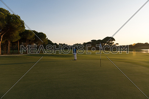 golf player hitting ball  with driver on course at beautiful sunset