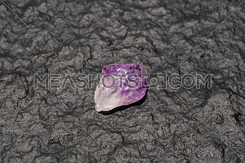 Crystals of amethyst on rock isolated on black stone background