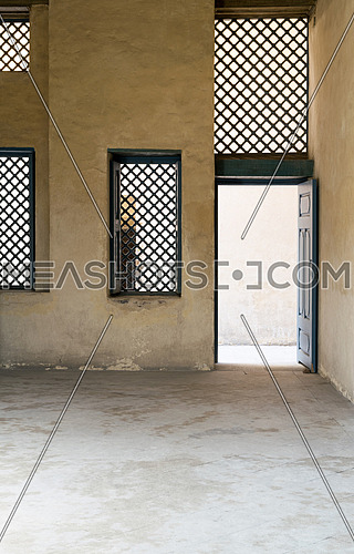 Blue vintage wooden windows with interleaved wooden grid (mashrabiya) and blue wooden door with plaster yellow wall