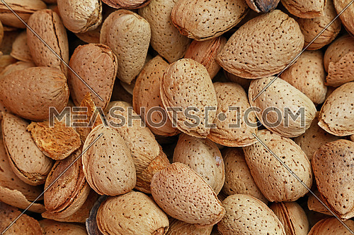 Whole raw brown almond nuts with shell on retail market, close up, background, high angle, elevated top view