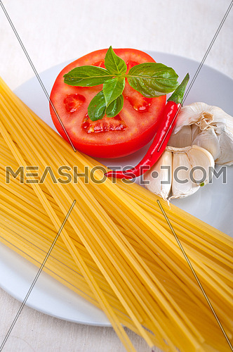 Italian spaghetti pasta tomato raw  ingredients basil garlic and red chili pepper