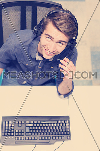 top view of a young smiling male call centre operator doing his job with a headset