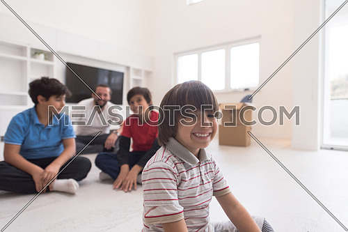 portrait of happy young boys with their dad sitting on the floor in a new modern home