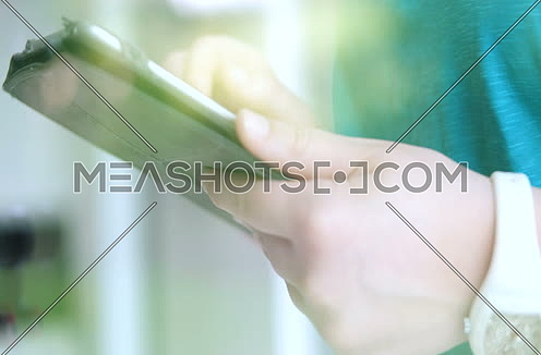 close up shot through window for a Woman using tablet at home by the window