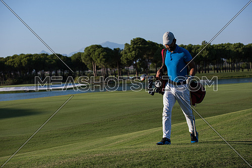 handsome middle eastern golf player carrying  bag  and walking at course to next hole