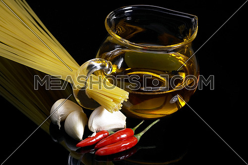 pasta garlic olive oil and red chili pepper ove black reflective surface