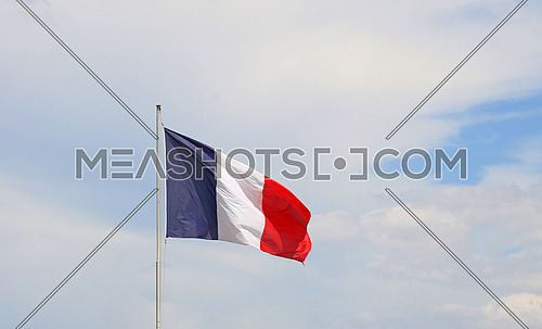 Close up flag of France waving and blowing in the wind over blue sky, low angle view
