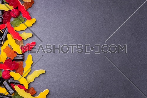 Many colored candies on dark background. Top view with copy space for your greetings.