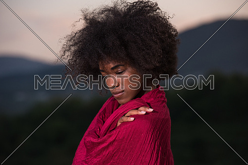 Outdoor portrait of young beautiful black woman with red scarf around shoulder
