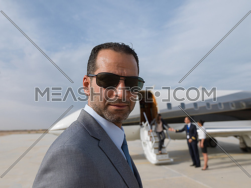 Portrait of a young successful middle eastern businessman at the airport in front of his private plane