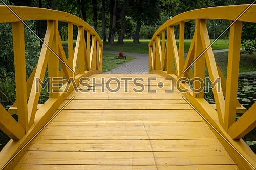 Empty arched wooden pedestrian bridge curving away in a receding perspective outdoors in a park