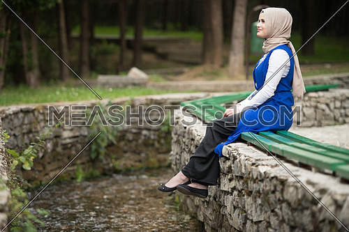 Portrait Of Young Muslim Woman Sitting On A Bench Next To The River
