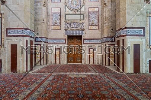 Old decorated stone wall with marble decorations and arabesque decorated wooden door in an al Refai historic public mosque, Cairo, Egypt