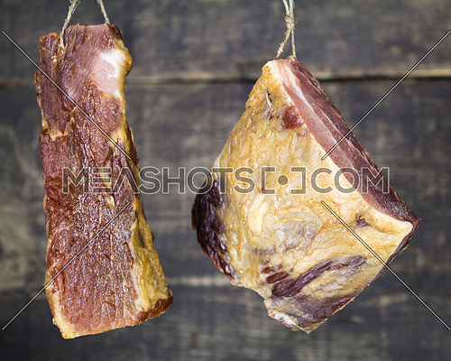 Smoked Pork Meat Hanging on the Rope Against Wooden Background