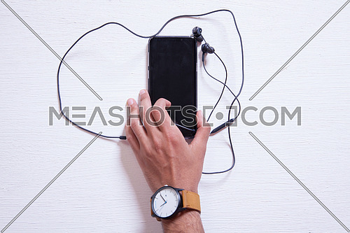 A mobile phone with headphones on a white table