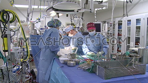 Tilt up long shot of operating room while medical team performing surgery