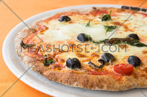 typical italian pizza with mozzarella, tomato cherry and olives  on white plate.