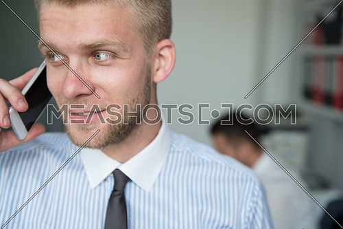 Happy Young Business Man Talking On Telephone In Modern Office Behind Him Sitting His Colleague