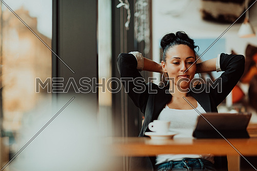a businesswoman sitting in a cafe on a break and using a tablet