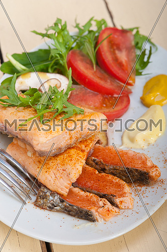 grilled fresh samon filet with vegetables salad tomato arugula mushroomsand paprika on top