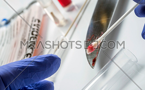 Expert police extracts traces of blood on a knife in scientific laboratory