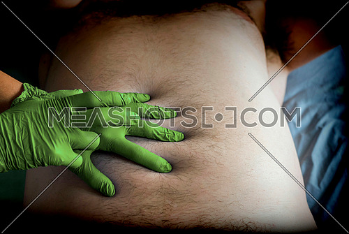 Doctor preparing abdominal palpation in a hospital, conceptual image, horizontal composition