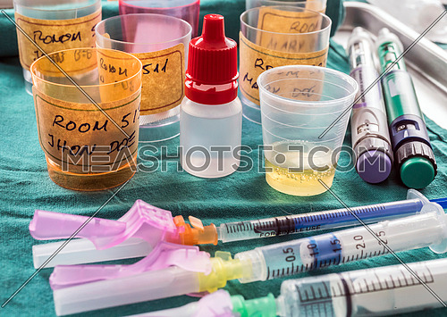 Diverse medication in glasses monodose along with insulin injectors in hospital, conceptual image, horizontal composition
