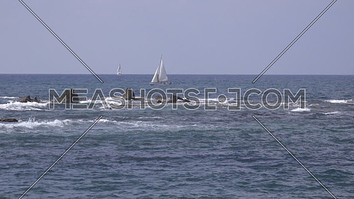 View of sailboat near dangerous jagged rocks along Tel Aviv coast