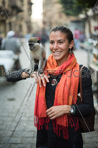 portrait of a young beautiful middle eastern woman who enjoys in the city with a monkey on her shoulder