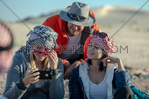 mid shot for group of tourists wearing bedouin traditions headscarf and taking selfies at Ain hodouda in Sinai at day