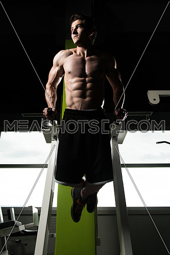 Young Muscular Fitness Bodybuilder Doing Heavy Weight Exercise For Triceps And Chest on Parallel Bars In The Gym