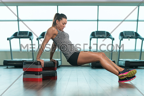 Young Woman Athlete Doing Triceps Exercise On Stepper As Part Of Bodybuilding Training