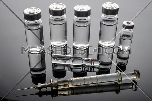 Vintage syringe next to vials with medication, conceptual image, horizontal composition