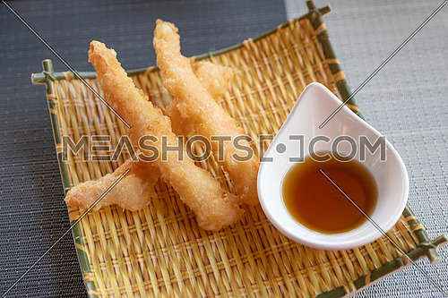 Prawns tempura with soy sauce on yellow bamboo plate. Seafood tempura dish of traditional asian cuisine