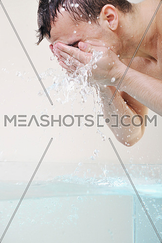 young man washing face with clean water and representing hygiene and mans beauty concept