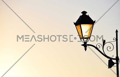 Street antique style lamp post with effect of shine from low light of sunset