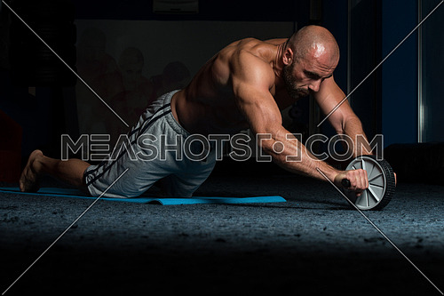 Young Man Exercising Fitness Workout For Abdominal With Toning Wheel