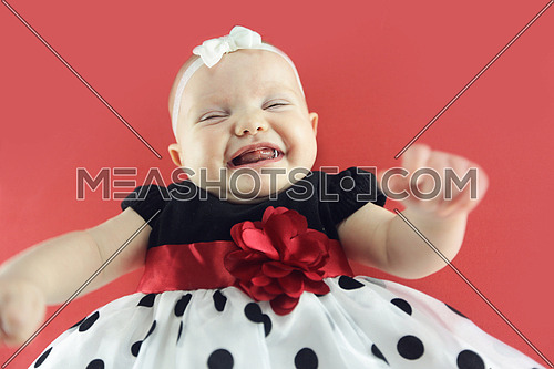 A cute baby wearing a dotted dress isolated on red