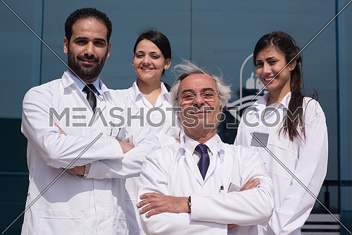 portrait of middle eastern team doctors in front of a large modern hospital