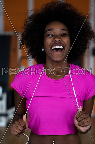 afro american woman running on a treadmill at the gym while listening music on earphones