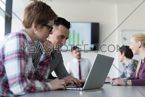 young startup  business people, couple working on laptop computer,  businesspeople group on meeting in background at office interior