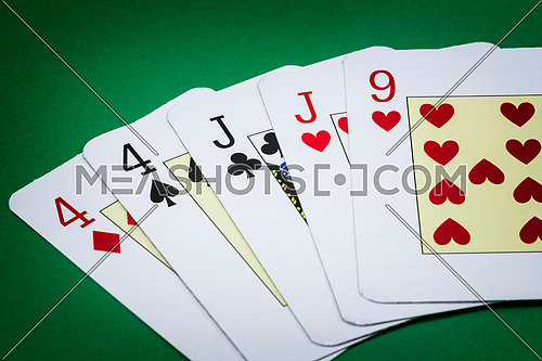 Poker hand call two pairs, consisting of two pairs of cards of the number four, two pairs of cards of j and a letter from the nine of hearts green background