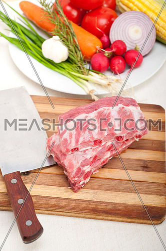 chopping fresh pork ribs with vegetables and herbs ready to cook