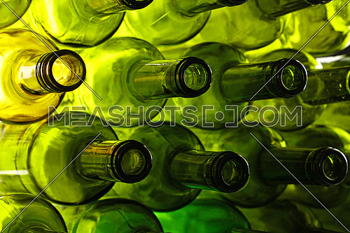 Close up stack of many empty washed green glass wine bottle necks, low angle side view